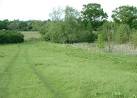 The pond is on the right, Jurassic Way climbs a field to a railway bridge - via Daymix