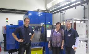 Ingmar Heil (GM Unikun), Sabine Loos (Kaufmännische Leitung KH) und Axel Zuleeg (CEO KH) vor zwei neuen Spritzgießmaschinen, lackiert im KH blau. (Foto KH)