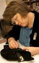 Mary Baughman uses tweezers to