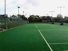 Looking across four artificial grass courts with the modern clubhouse, - via Daymix