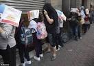 Chinese customers hide their faces as they wait to collect free