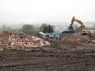 The excavator is loading a machine that crushes the bricks and rubble into a - via Daymix
